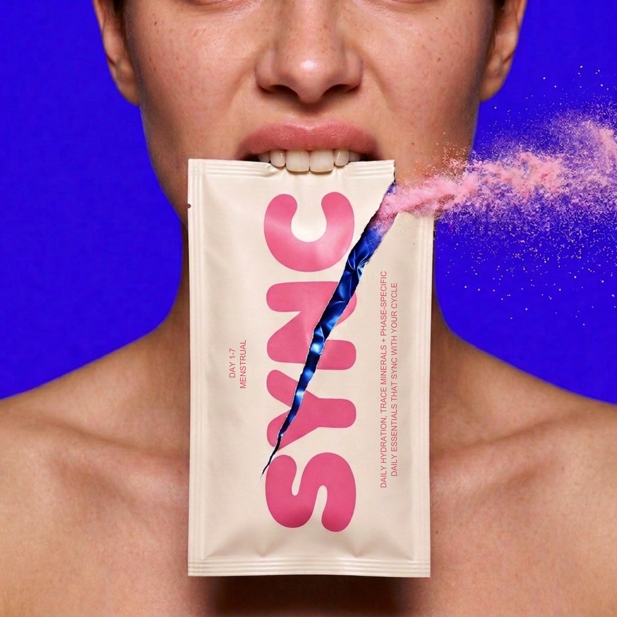 A woman tearing open a Sync stick pack with her teeth, pink powder bursting out